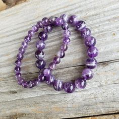 "Very pretty! February birthstone. Genuine, natural purple Amethyst gemstone stretch bracelet. 8mm - LARGE - fits more snug than smaller beads 10mm - LARGE - fits more snug than smaller beads Lengths approximate. 8mm: 7 3/4\" stretching to about 8\" or a little more 10mm: 8\" stretching to about 8 1/4\" or a little more 🌟 7 3/4\" & 8\" generally considered \"One Size Fits Most\" CAN customize length - send me a message 🖤 NO TWO ALIKE 🖤 Some are dark purple, some a light, some mixed dark a Purple Amethyst Round Stretch Bracelet, Purple Amethyst Stretch Bracelet, Purple Stretch Bracelet With Natural Stones, Purple Natural Stones Stretch Bracelet, Purple Amethyst Stretch Bracelet With Natural Stones, Amethyst Bracelet, February Birth Stone, Amethyst Gemstone, Purple Amethyst