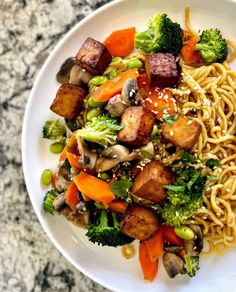 a white plate topped with broccoli, carrots and tofu stir fry