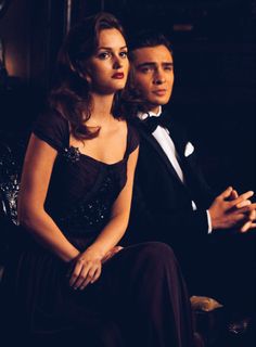 a man in a tuxedo sitting next to a woman wearing a black dress