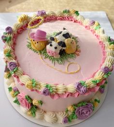 a cake decorated with flowers and two small cows on top of the frosted cake