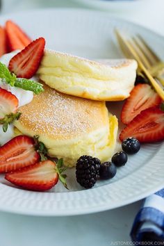 pancakes with berries and powdered sugar on a white plate