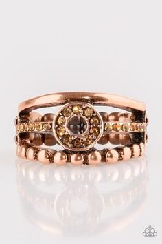 A smooth and dotted copper band flank a topaz rhinestone encrusted band, creating glittery layers across the finger. Encrusted in golden topaz rhinestones, a circular frame is pressed into the center of the bands for a refined finish. Features a dainty stretchy band for a flexible fit. Sold as one individual ring. Adjustable Crystal Ring With Rhinestones, Adjustable Crystal Rhinestone Ring, Adjustable Gold Crystal Ring, Gold Topaz Crystal Ring, Gold Rings With Bling, Elegant Rose Gold Copper Rings, Gold Copper Round Ring, Adjustable Gold Crystal Ring With Bling, Adjustable Gold Crystal Bling Ring