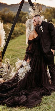 a man and woman are kissing in front of an altar with feathers on the grass