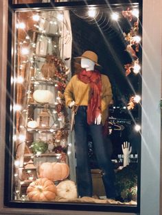 a mannequin dressed in a yellow sweater and hat with pumpkins on display