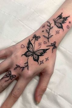 a woman's hand with tattoos on it and butterflies flying around the wrist,