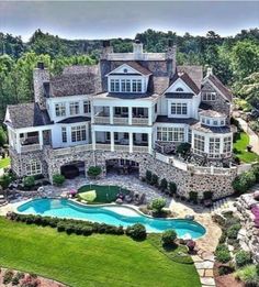 an aerial view of a large house with a pool in the front yard and landscaping around it