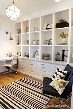 an office with white bookcases and black chair