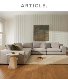 a living room with white walls and wood floors, an l shaped couch is featured in the article article article