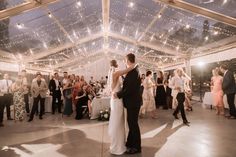 a bride and groom dance on the dance floor in front of their guests at a wedding reception