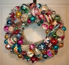 a christmas wreath hanging on the door with ornaments all over it's front and side