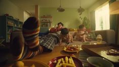 three people sitting on a couch in a living room with food and drinks around them