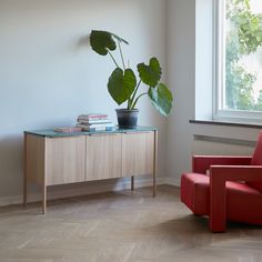 a red chair sitting next to a table with a potted plant on top of it