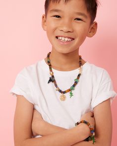 a young boy wearing a white shirt and beaded necklace