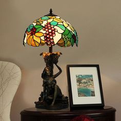 a lamp sitting on top of a wooden table next to a framed photo and an art piece