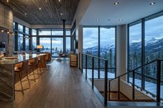 an open kitchen and living room area with large windows overlooking the mountain range at night