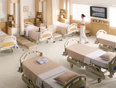 a hospital room filled with lots of beds and nurses in white gowns standing around