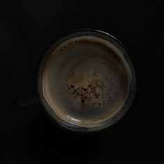 a close up of a cup of coffee on a black surface with some brown spots