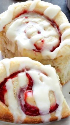 two strawberry rolls on a plate with strawberries in the background