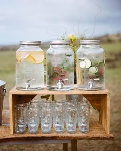 mason jars filled with water, lemons and cucumbers on a wooden table