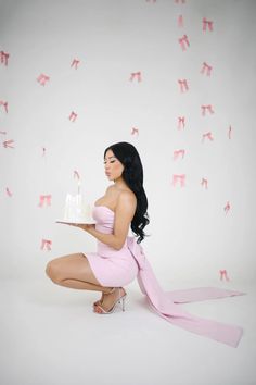 a woman kneeling down with a cake in front of her