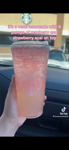 someone holding up a pink drink in their hand