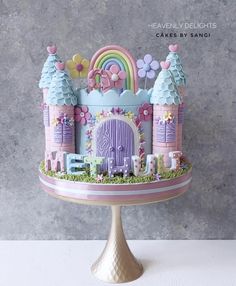 there is a cake that looks like a fairy castle on top of a stand with flowers and rainbows