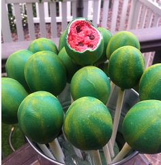 a bunch of green fruit sitting on top of a metal bowl filled with watermelon