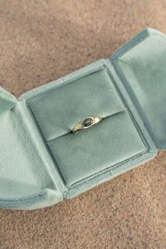 an open ring box on the ground with a gold band and a diamond in it