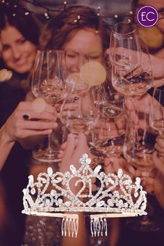 a group of people holding up wine glasses in front of a tiara with the number twenty one on it