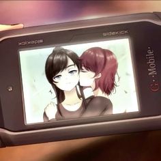 a person holding up a cell phone with an image of two people kissing on the screen