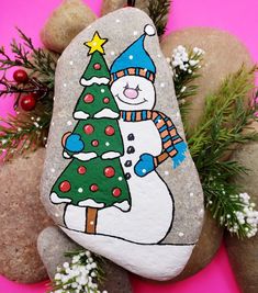 a painted rock with a snowman holding a christmas tree on it's face