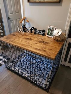 a wooden table with a metal cage on top and pictures on the wall next to it