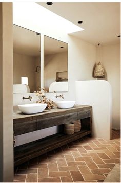 two white sinks sitting on top of a wooden counter next to a wall mounted mirror