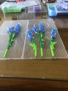 three plastic flowers sitting on top of a table next to some beads and glues