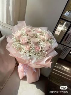 a bouquet of pink roses and baby's breath is sitting on a couch in front of a mirror