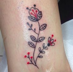 a small flower tattoo on the side of a woman's leg, with red and white flowers