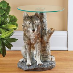 a glass table with a wolf figurine on it next to a potted plant