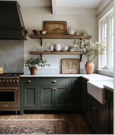 a kitchen with dark green cabinets and white counter tops, an open shelf above the stove