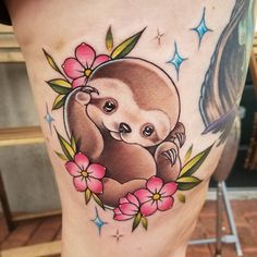 a sloth tattoo on the side of a woman's leg with flowers around it