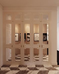 an empty room with marble flooring and white walls that have mirrors on the doors