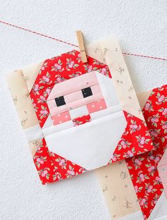 a santa clause quilted onto the side of a red piece of fabric hanging from a clothes line