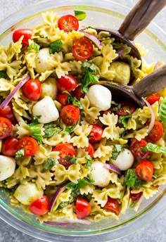 a bowl filled with pasta salad topped with tomatoes and mozzarella