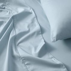 an unmade bed with white sheets and pillows