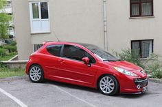 a red car parked in a parking lot next to a building