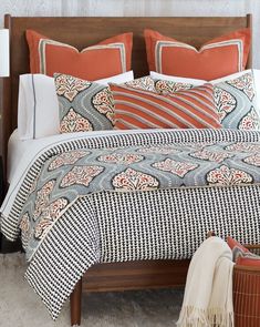 a bed with an orange and white comforter on it next to a night stand