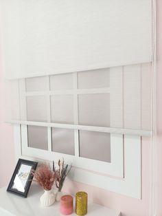 a window with white blinds and pink walls in the background, along with vases on a table