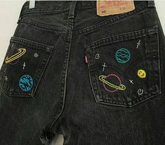 a pair of jeans with embroidered planets on them