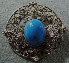 I am offering you this truly exquisite vintage silver tone raised relief ornate scrolled etched filigree round pin brooch with a large oval shaped glass blue stone prong set in the center. There is endless amounts of open work, heavily etched , raised relief filigree. It is measuring app. 2 inches in diameter. It is a must have for the vintage jewelry collector. Buyer pays all shipping and handling fees, we will always combine shipping. Murano Glass Necklaces, Glass Necklace, Pin Brooch, Blue Stone, Vintage Silver, Prong Setting, Brooch Pin, Brooches, Etsy Gifts