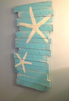 a wooden sign with starfish painted on it hanging on the side of a wall