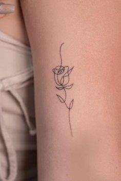 a woman's thigh with a small flower tattoo on her left side ribcage